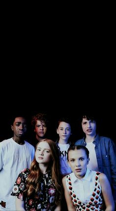 a group of young people standing next to each other in front of a black background