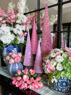 colorful vases and flowers on a table in front of a mirror with pink and white flowers