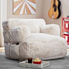 a living room with a white chair and guitar on the wall