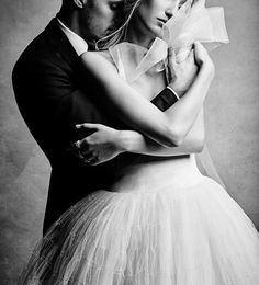 a black and white photo of a man and woman in wedding attire hugging each other