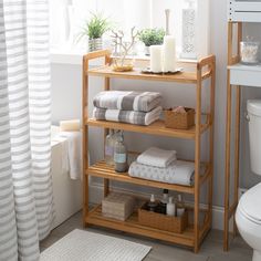 a bathroom shelf with towels, candles and other items on it in front of a window