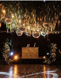 a man and woman standing in front of a wooden table with disco balls hanging from the ceiling