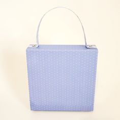 a small blue polka dot purse on a white background with the handle extended to show it's inner lining