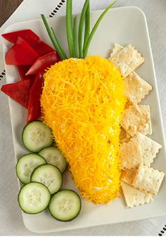 a white plate topped with cheese and crackers next to cucumbers