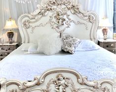 a white bed with ornate headboard and foot board