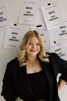 a woman standing in front of a wall with papers on it and her arms behind her back