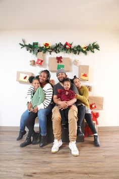 a group of people sitting next to each other in front of boxes and presents on the wall