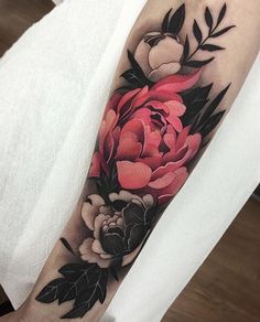 a woman's arm with flowers and leaves on it