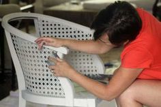 a woman kneeling down on a white chair with her hand on the back of it