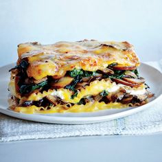 a white plate topped with lasagna covered in cheese and spinach toppings