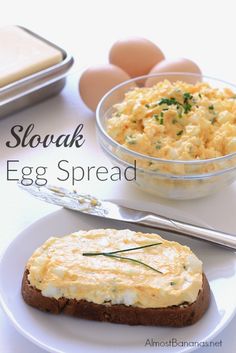 an egg spread is on a white plate next to bread and eggs in a bowl