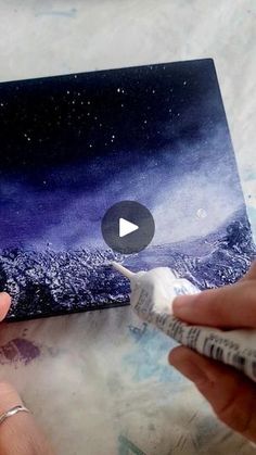 someone is using a toothbrush to paint a painting on a piece of paper with watercolors