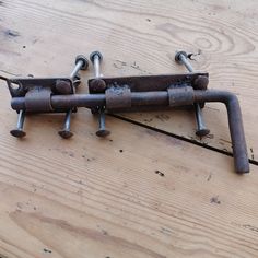 an old metal object sitting on top of a wooden table next to some screws