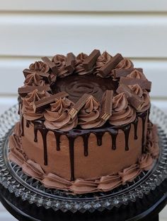 a chocolate cake sitting on top of a black plate covered in frosting and chocolate icing