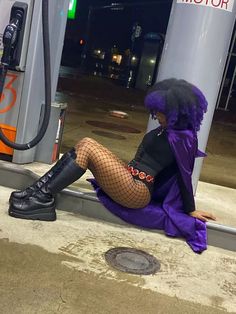 a woman sitting on the ground next to a gas pump wearing fishnet stockings and boots