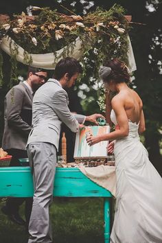 a bride and groom are getting ready to cut the cake at their outdoor wedding ceremony