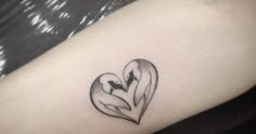 a heart shaped tattoo on the arm with two birds inside it and an arrow in the middle