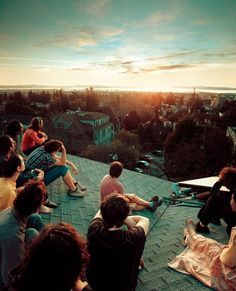 group of people sitting on roof watching sunset