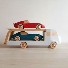 two wooden toy cars are stacked on top of each other in front of a white wall