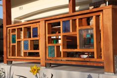 a wooden book shelf sitting on the side of a building next to a yellow flower