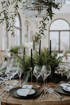 the table is set with place settings, candles and greenery for an elegant dinner