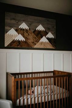 a baby's crib with mountains painted on the wall in front of it