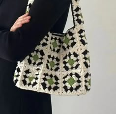 a woman is holding a crocheted purse