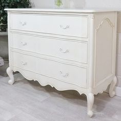 a white dresser sitting next to a potted plant