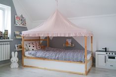 a child's bed with a pink canopy over it in the corner of a room