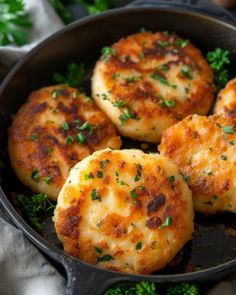 four crab cakes in a cast iron skillet with parsley sprinkled on top