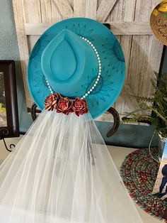 a blue hat on top of a table with a veil over it's head