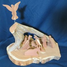 a figurine of people standing in front of a tree stump with a bird flying over it