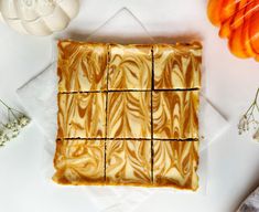 a white plate topped with slices of cake next to flowers and an orange slice on top of it