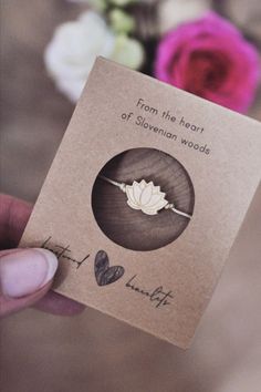 a person holding up a card that says from the heart of stevens woods with flowers in the background