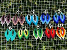 several pairs of colorful earrings are on display behind a wire mesh fence with numbers in the background