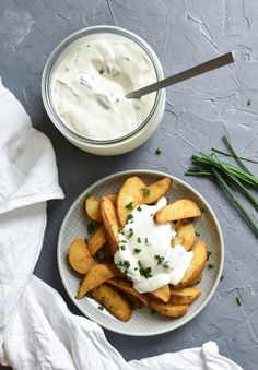 a plate with french fries and yogurt on it next to a bowl of ranch dressing