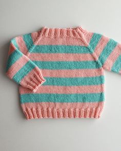 a pink and blue sweater sitting on top of a white table