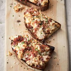 three slices of pizza sitting on top of a wooden cutting board with cheese and toppings