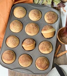 muffins in a baking pan with cinnamon sticks and other items around the muffin tray