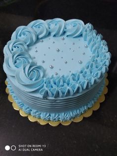 a blue frosted cake with gold trimmings on a black counter top,