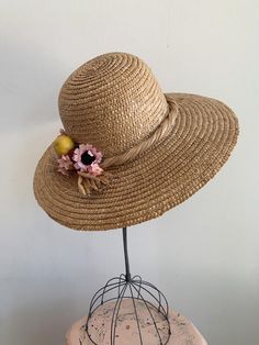 This is a vintage 1950's straw sun hat. The hat is intricately woven with a braided section across the brim. There is also pink tone faux floral details. By the faux flowers there are also plastic faux fruit adding a pop of color and texture. The hat is in excellent condition.Measurements:Circumference: 21" | Inside Depth: 5.5" | Brim Depth: 4" | Brim Circumference: 46"Unless otherwise stated all vintage items are used and may have minor to moderate wear or discoloration considering the age of t Pink Straw Fedora Hat, Pink Fedora Straw Hat, Summer Pink Straw Hat For Garden Party, Pink Summer Straw Hat For Garden Party, Pink Straw Hat With Short Brim, Vintage Natural Color Adjustable Hats, Adjustable Vintage Panama Hat, Vintage Straw Hat For Beach, Adjustable Retro Straw Hat For Vacation