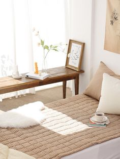 a bed sitting in a bedroom next to a table with a vase on top of it