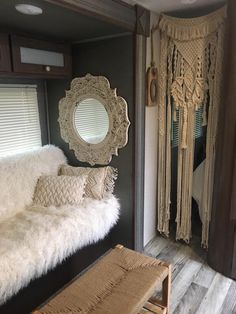 a bed with white fur and pillows in a room next to a mirror on the wall