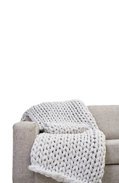 a white knitted blanket sitting on top of a couch next to a gray chair