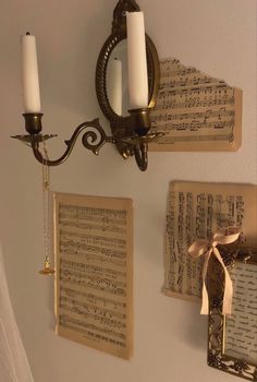 two wall sconces hanging on the wall with sheet music notes and candle holders