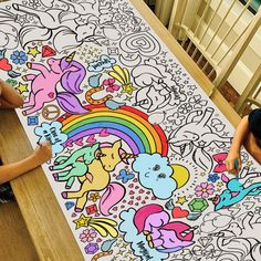 two children are sitting at a table with a large coloring book on top of it