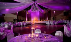 a dance floor with purple lights and white drapes on the ceiling is set up for a wedding reception