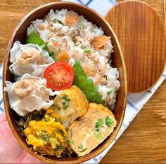 a wooden bowl filled with rice, meat and veggies