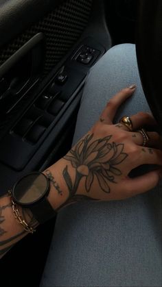 a woman's arm with tattoos on it sitting next to a car steering wheel