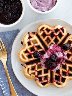 a white plate topped with waffles covered in blueberry sauce